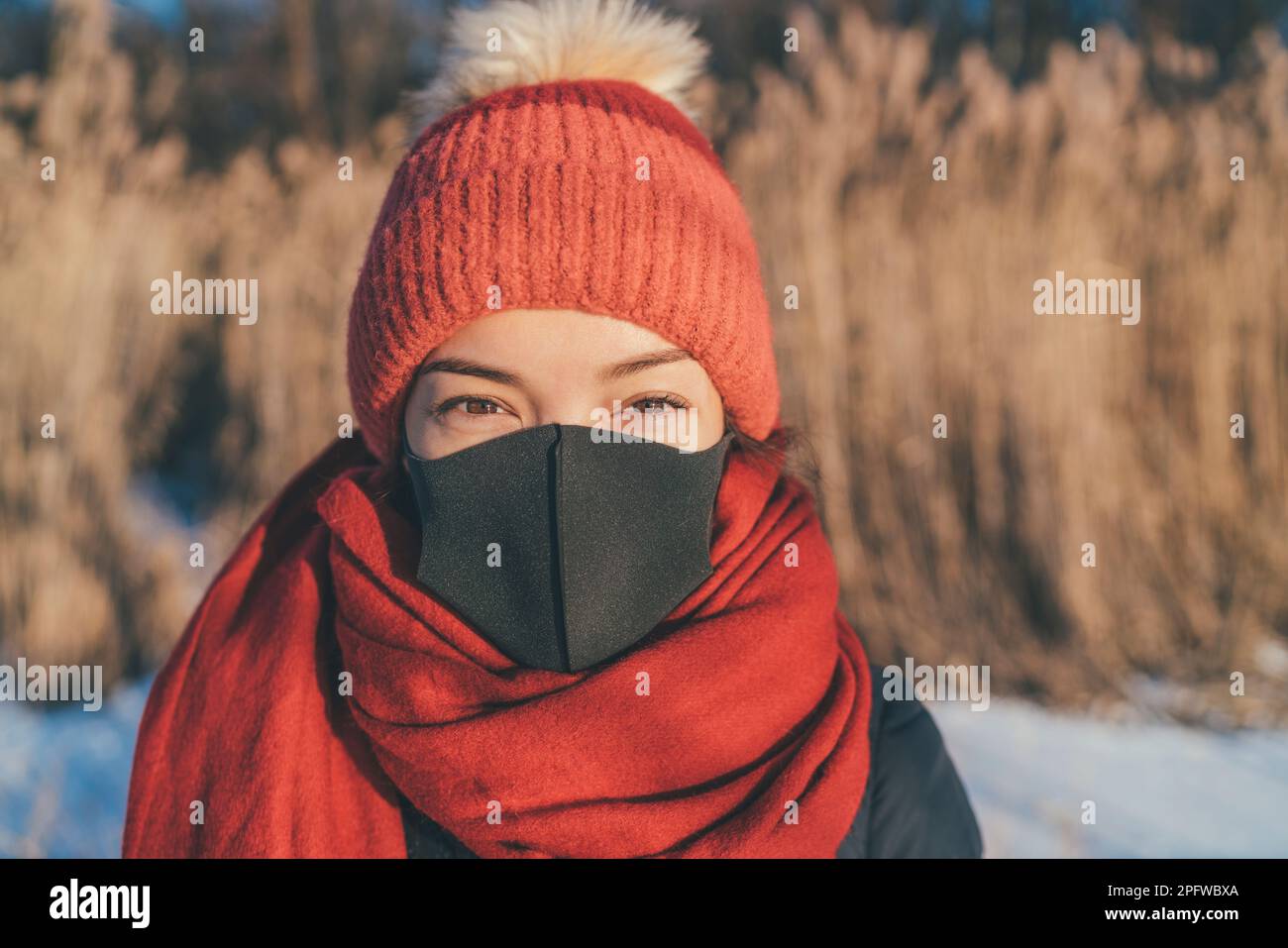 Maschera viso con ritratto donna asiatica in inverno all'aperto. Ragazza con accessori per climi freddi, cappello, sciarpa per brina Foto Stock