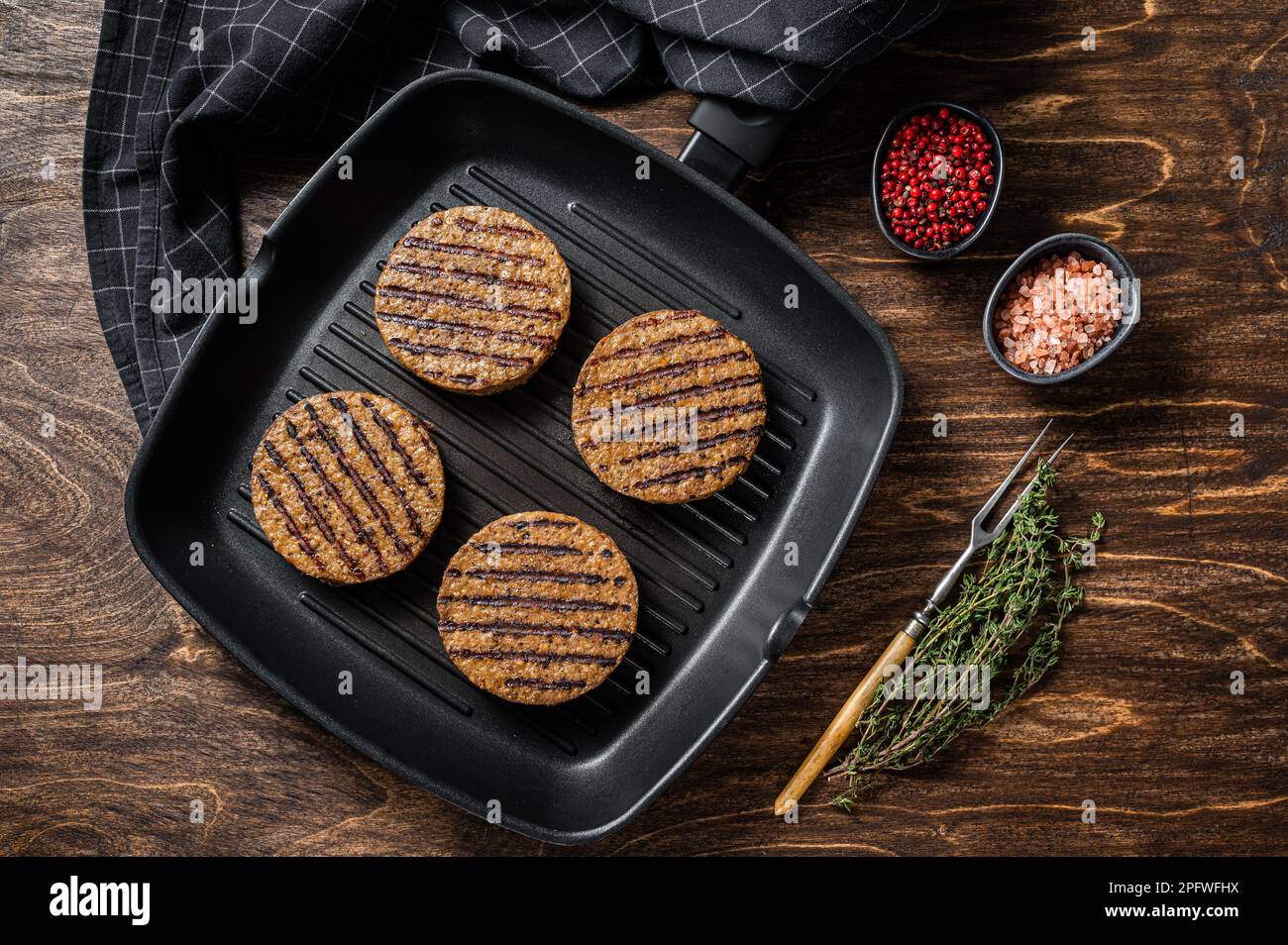 Hamburger di carne alla griglia a base di piante vegetali, cotolette vegane sulla padella alla griglia. Sfondo di legno. Vista dall'alto. Foto Stock