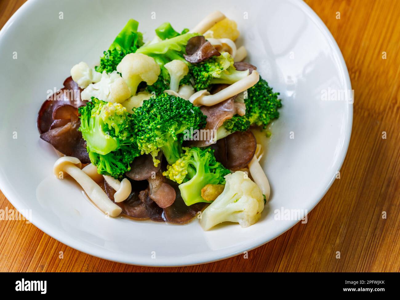 Menu di cibi salutari, funghi fritti in padella, cavolfiore e broccoli, cibo di verdure misto tailandese sano su un piatto bianco. Immagine ravvicinata, vista dall'alto. Foto Stock