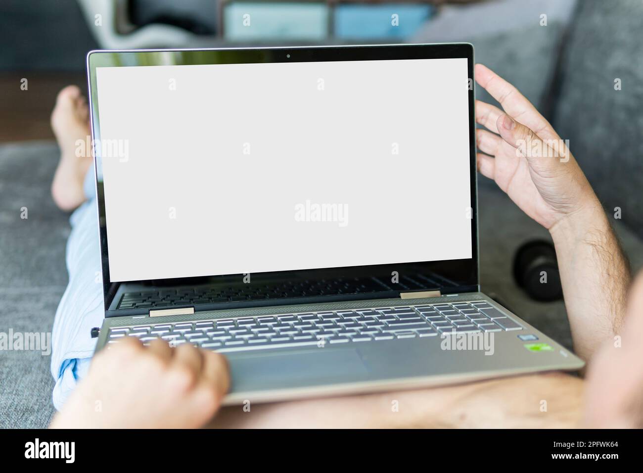 Immagine closeup di un uomo sdraiato su un letto che lavora su un computer portatile. Foto POV di un uomo che si rilassa in camera da letto utilizzando un computer touch screen. Spazio di copia. Lo spazio Foto Stock