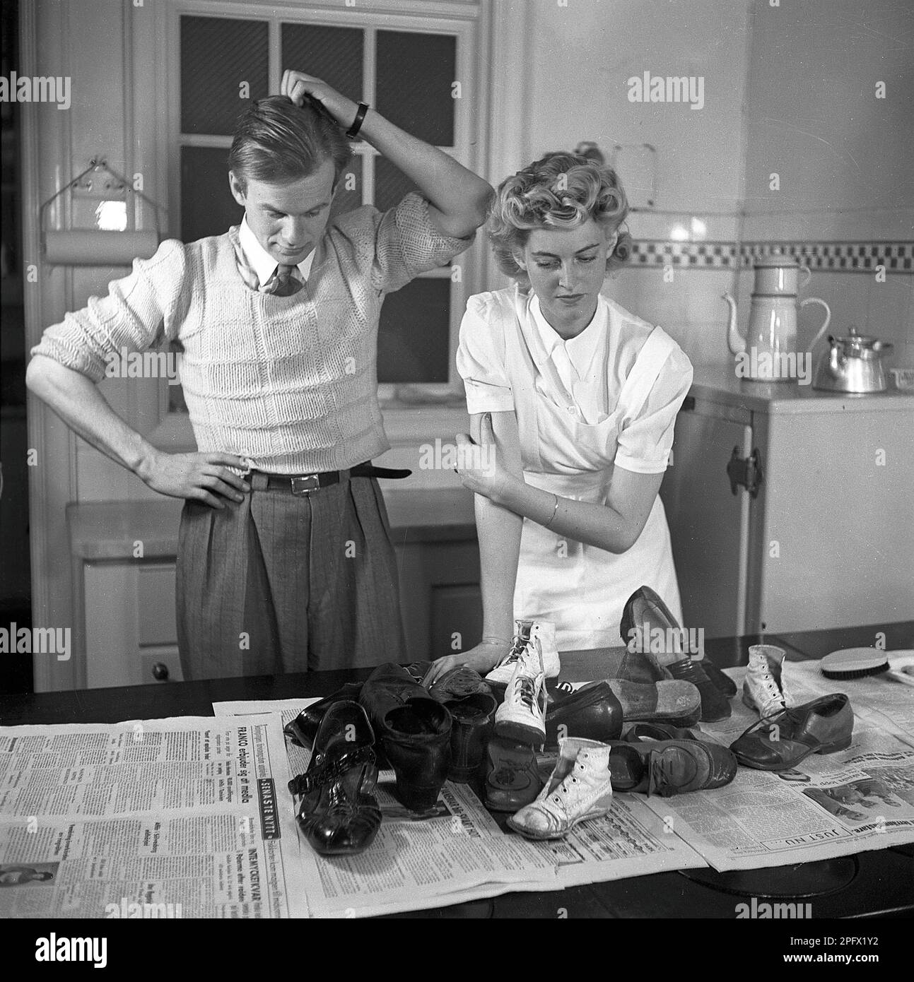 Scarpe negli anni '1940s. Un paio di scarpe davanti a loro sul tavolo da cucina. Le scarpe sono usate per un po' di tempo ed hanno bisogno di un lucidante. Svezia 1943 Kristoffersson Ref D59-1 Foto Stock