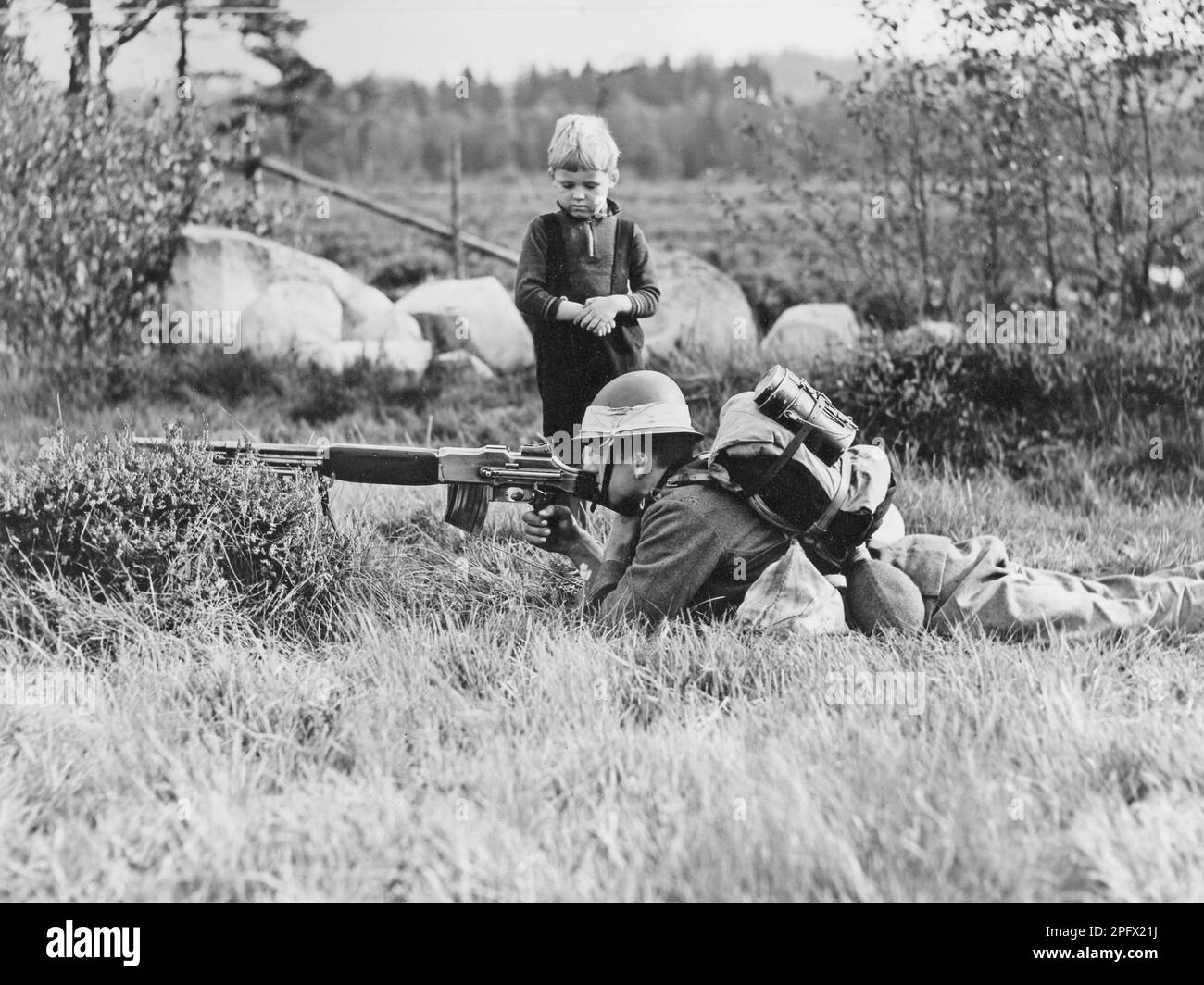 La seconda guerra mondiale sta per arrivare. La Svezia equipaggia la difesa e gli esercizi nell'autunno del 1938 a Småland. Un soldato si trova campo-come nel campo nella natura Småland e mira con il suo fucile. Un ragazzino si alza di lato e si guarda meravigliato. 18 settembre 1938 Foto Stock