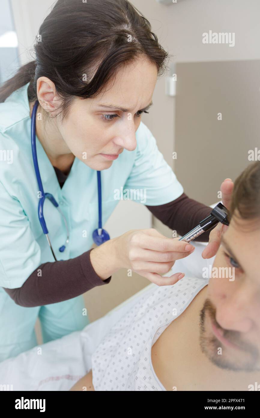 medico ent che guarda i pazienti all'orecchio con uno strumento Foto Stock