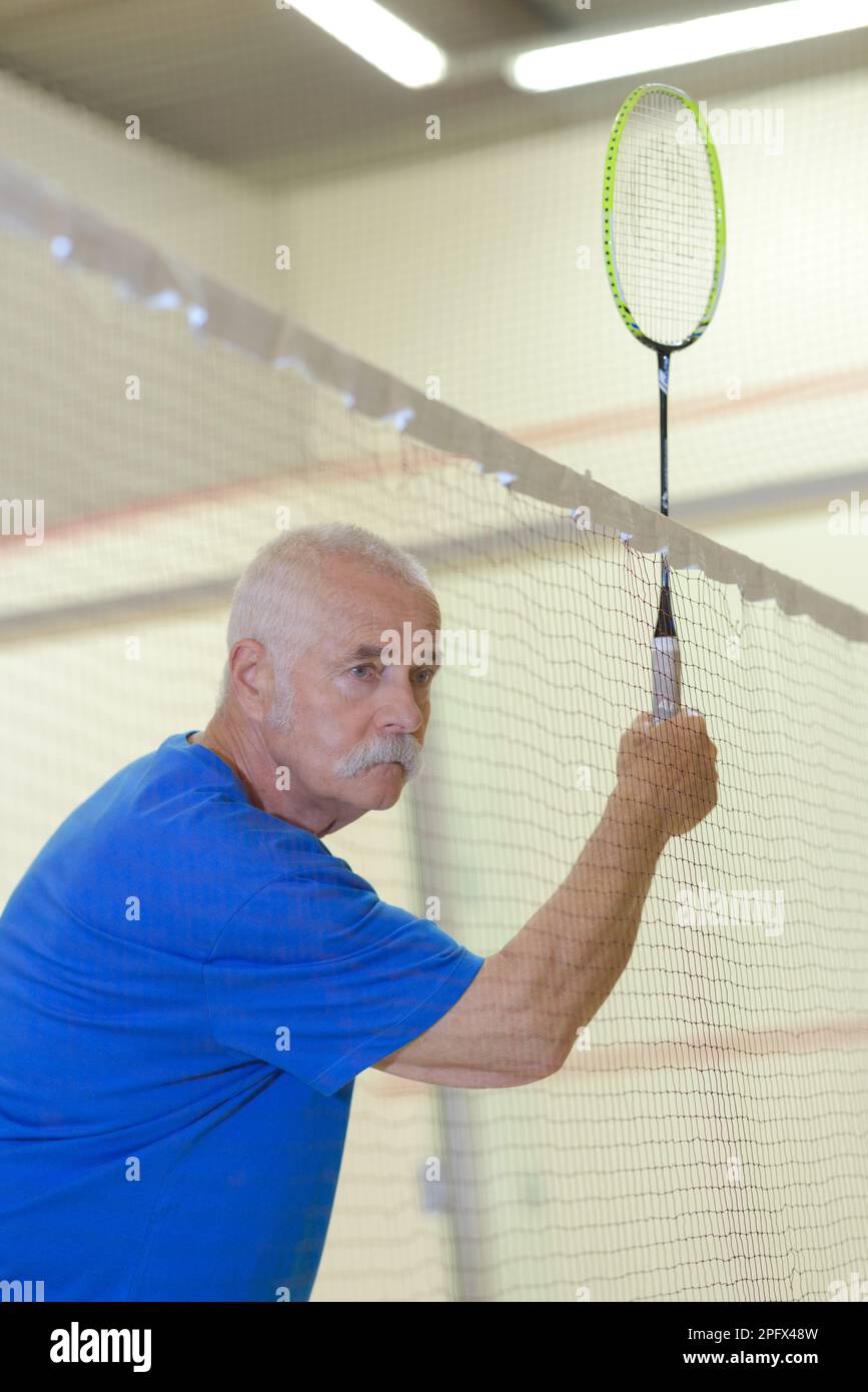 il vecchio che fa un servizio mentre gioca il badminton Foto Stock