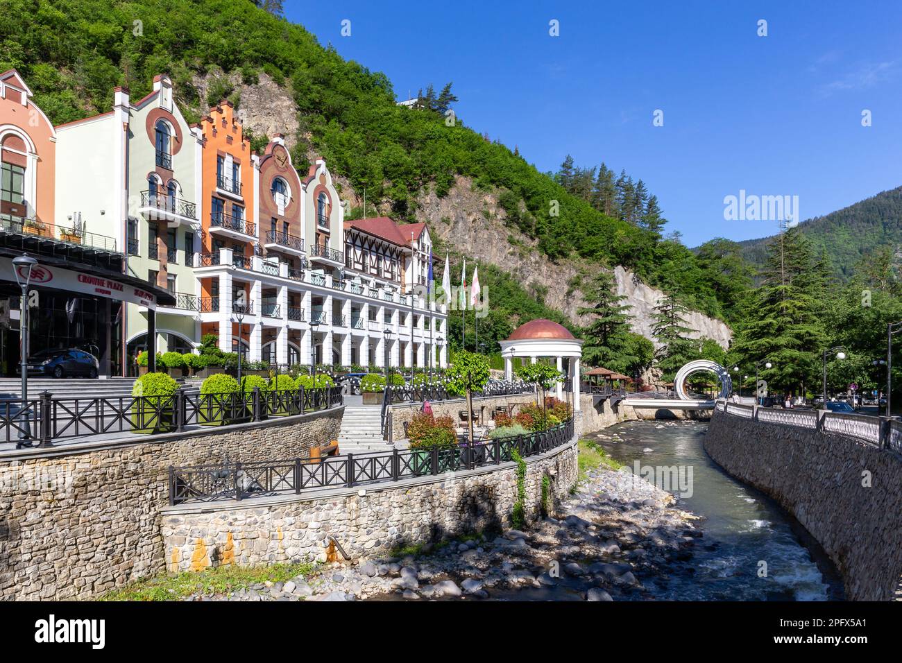 Borjomi, Georgia, 08.06.2021. Il paesaggio della città di Borjomi con il Crowne Plaza Borjomi, un IHG Hotel, il fiume Kura e il Mobius Loop Bridge. Foto Stock
