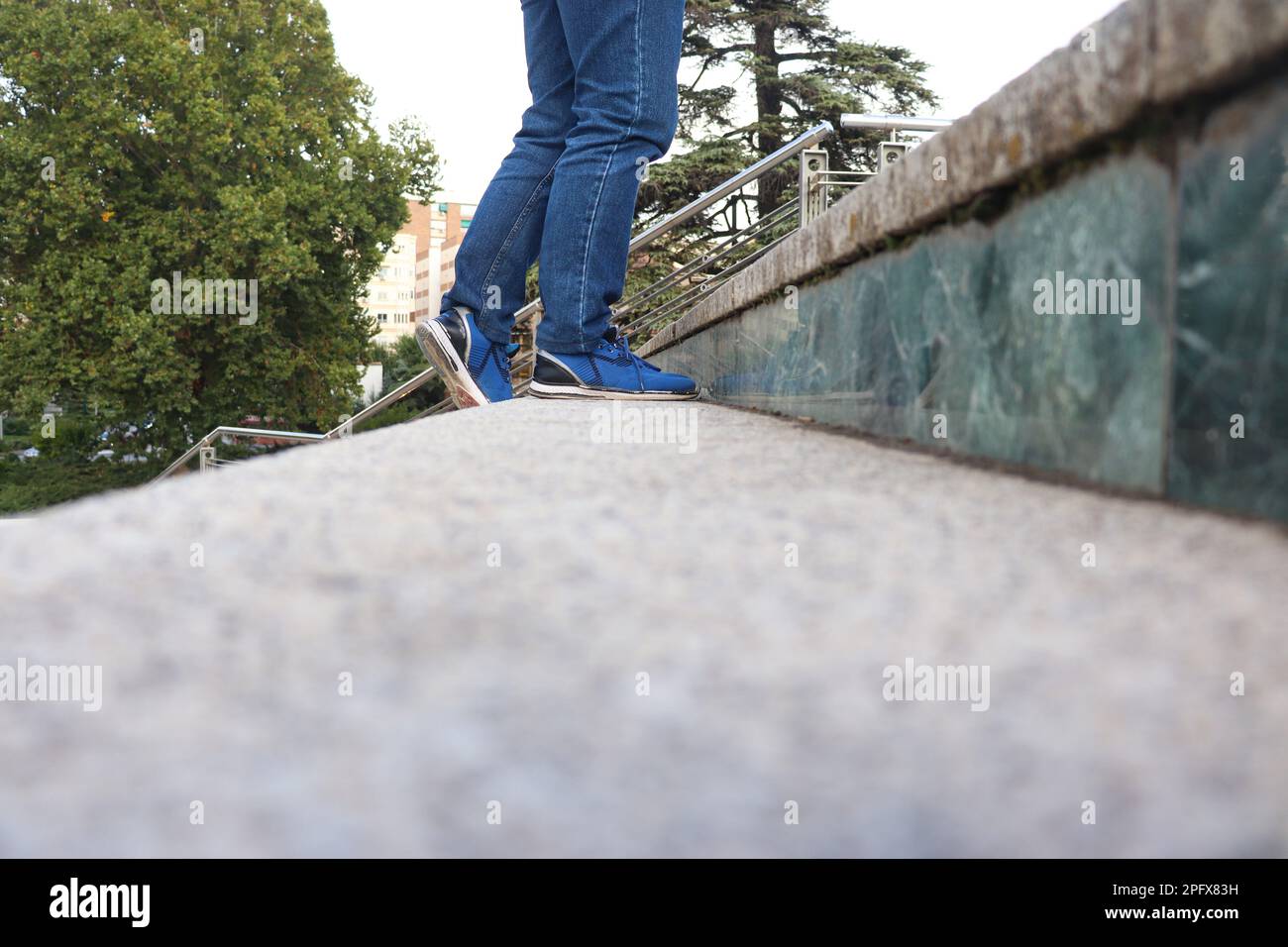 Una persona con jeans blu e scarpe che camminano sulle scale Foto Stock