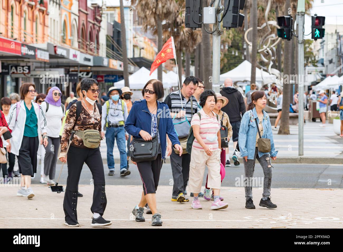 Un grande gruppo di turisti cinesi che camminano dal corso verso Manly Beach la domenica a Sydney, Australia Foto Stock
