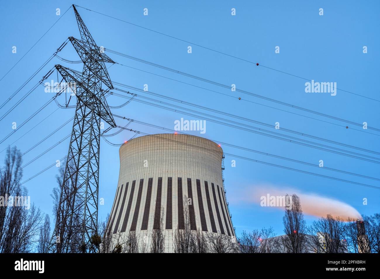 Un pilone elettrico e la pila di fumo di una centrale elettrica visto a Berlino, Germania Foto Stock