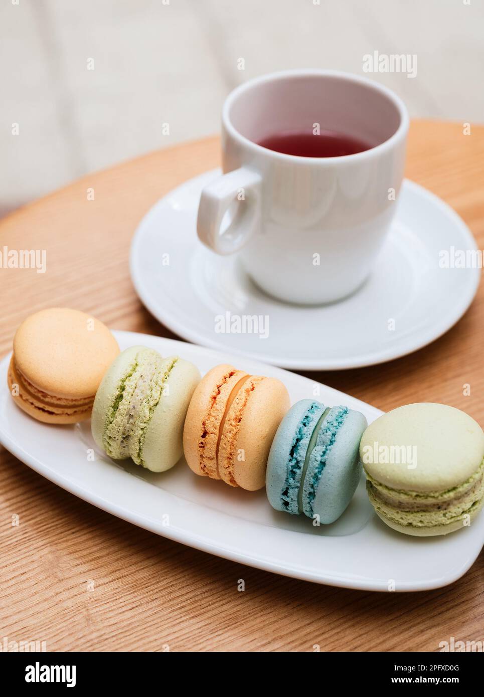 Biscotti macaroon di colori diversi su un piatto bianco. Cibo francese a base di farina di mandorle. Dolce con tè Foto Stock