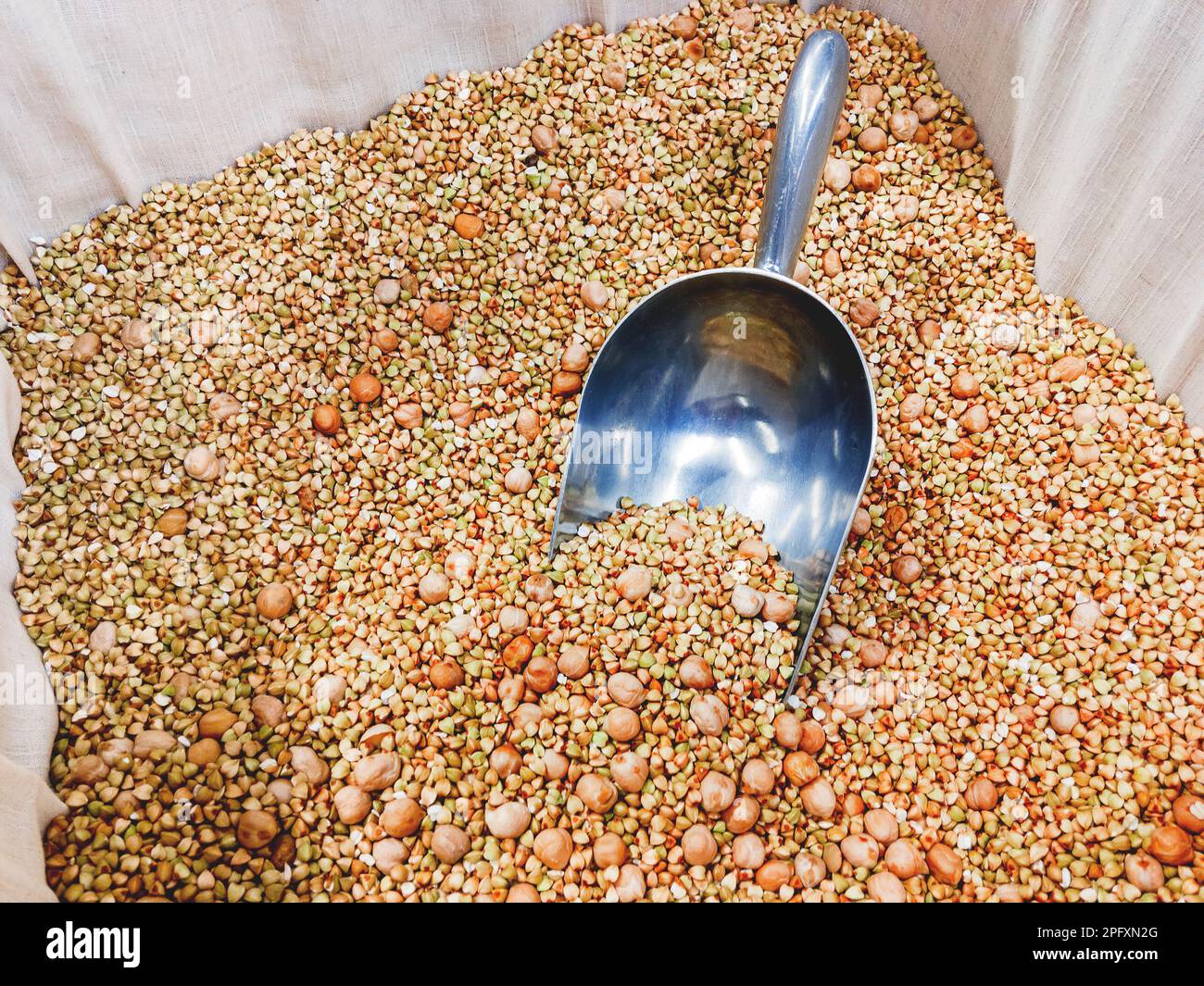 Scatola con grano saraceno verde e ceci. Una paletta speciale per spruzzare grits nelle confezioni. Il display nel negozio. Foto Stock