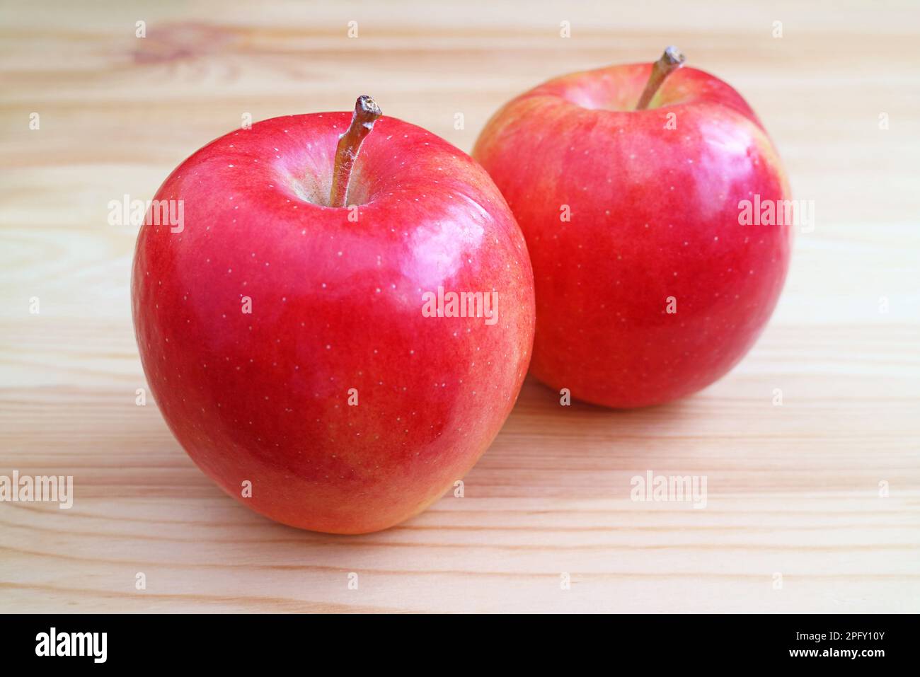 Coppia di mela rossa fresca matura isolata su tavolo di legno Foto Stock