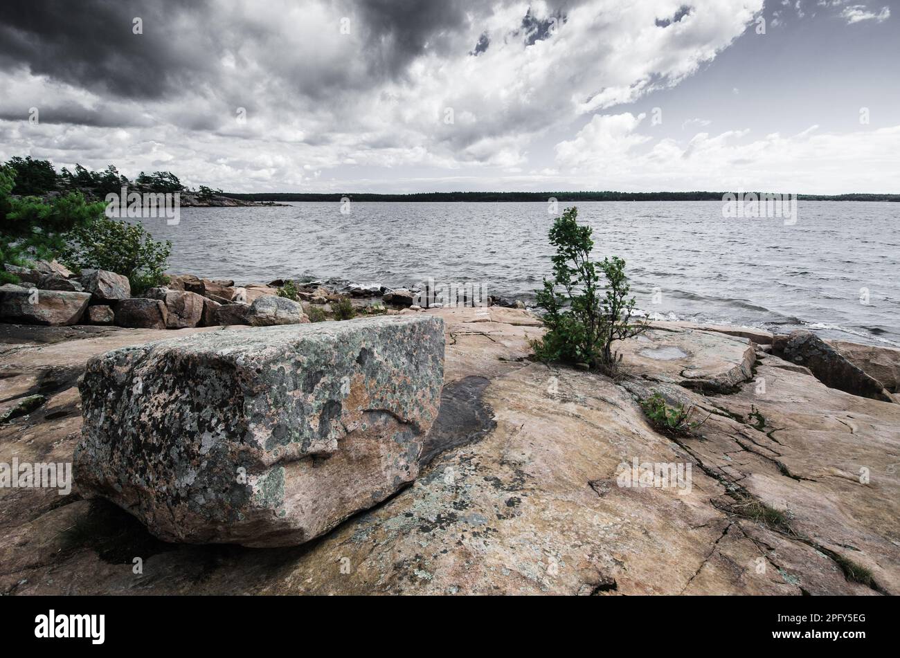 Una grande formazione rocciosa in primo piano, situata sul bordo di un lago tranquillo Foto Stock