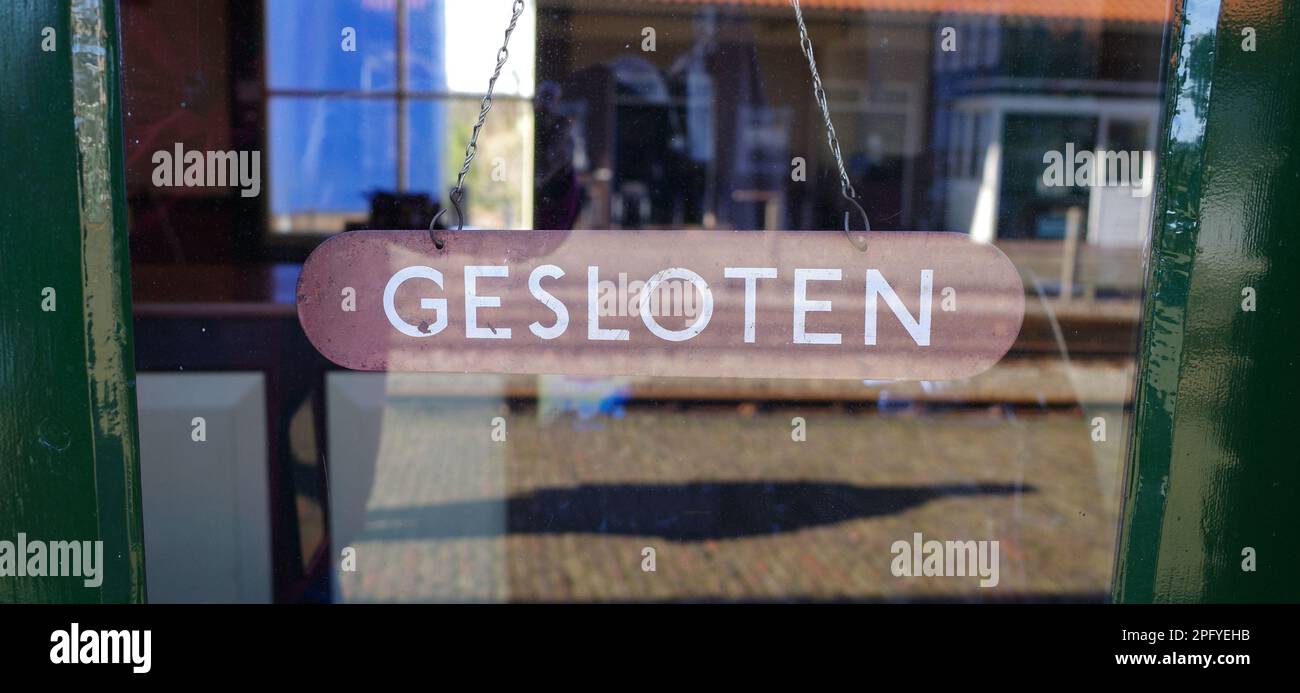 Un piatto di legno vecchio stile appeso a una catena con la parola 'gesloten' che significa chiuso. Foto Stock