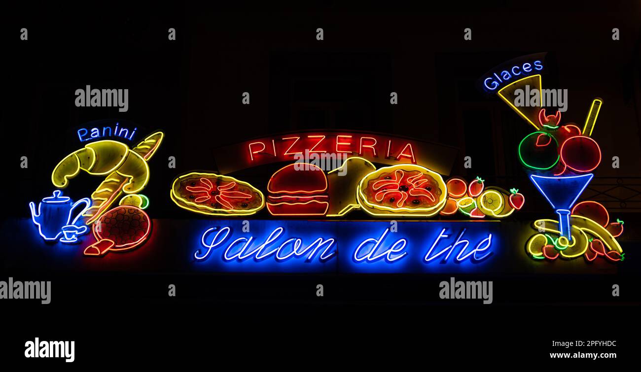 Lourdes, Francia - 3 gennaio 2023: Insegne luminose e immagini sopra una pizzeria, pasticceria e fast food Foto Stock