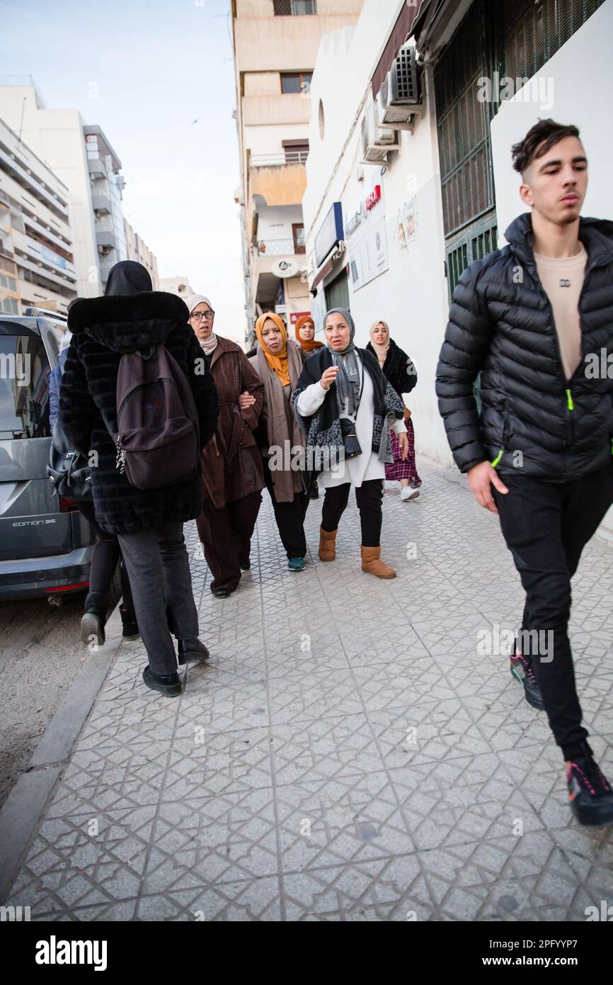 Marocchini locali a piedi lungo un marciapiede a Fes Foto Stock