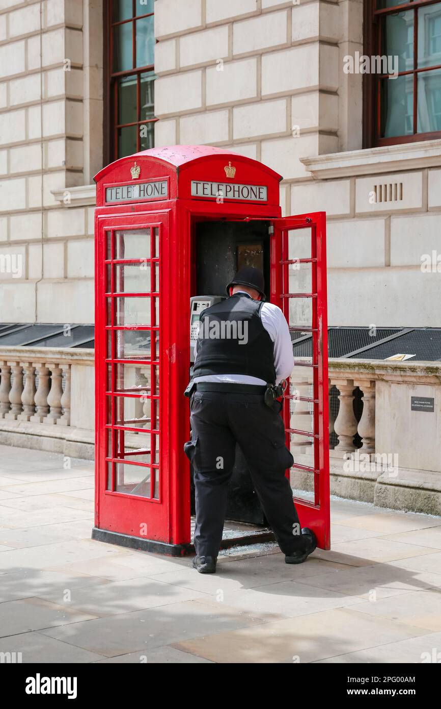 Londra, Regno Unito. 07 giu 2022. Un poliziotto si spazza su vetro rotto in una cassetta telefonica rossa in Parliament Street, Londra. © Waldemar Sikora Foto Stock