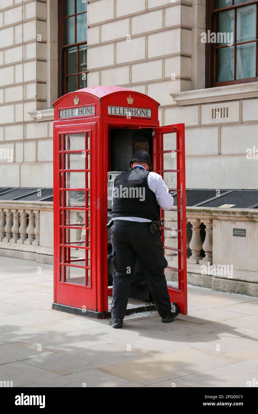 Londra, Regno Unito. 07 giu 2022. Un poliziotto si spazza su vetro rotto in una cassetta telefonica rossa in Parliament Street, Londra. © Waldemar Sikora Foto Stock