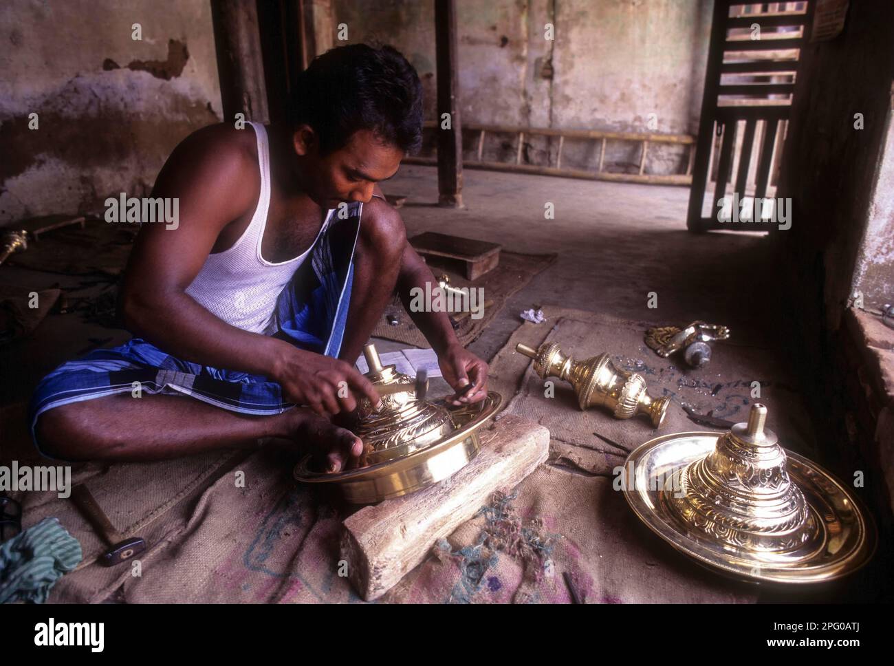 Artigiano che lavora su lampada di ottone, Nachiyar Koil vicino Thanjavur, Tamil Nadu, India Foto Stock