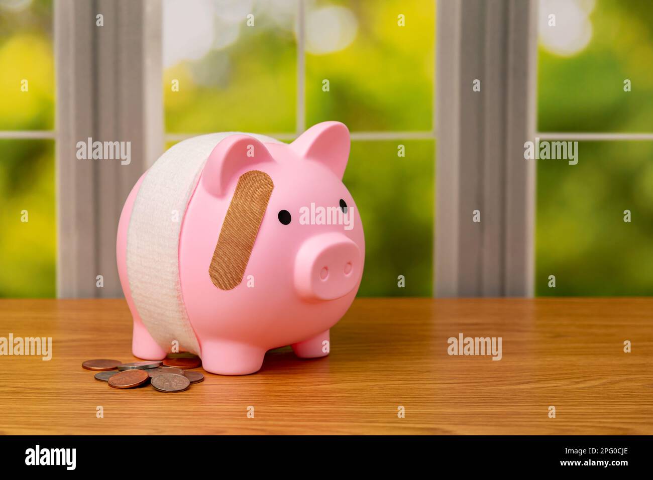 Banca di maialino con bendaggio e monete. Pensionamento, fallimento bancario, salute finanziaria e concetto di pianificazione. Foto Stock