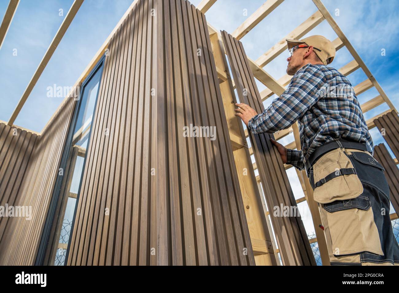 Caucasian General Construction Worker nel suo edificio 40s piccolo giardino moderno capanno utilizzando legno e materiali compositi. Foto Stock