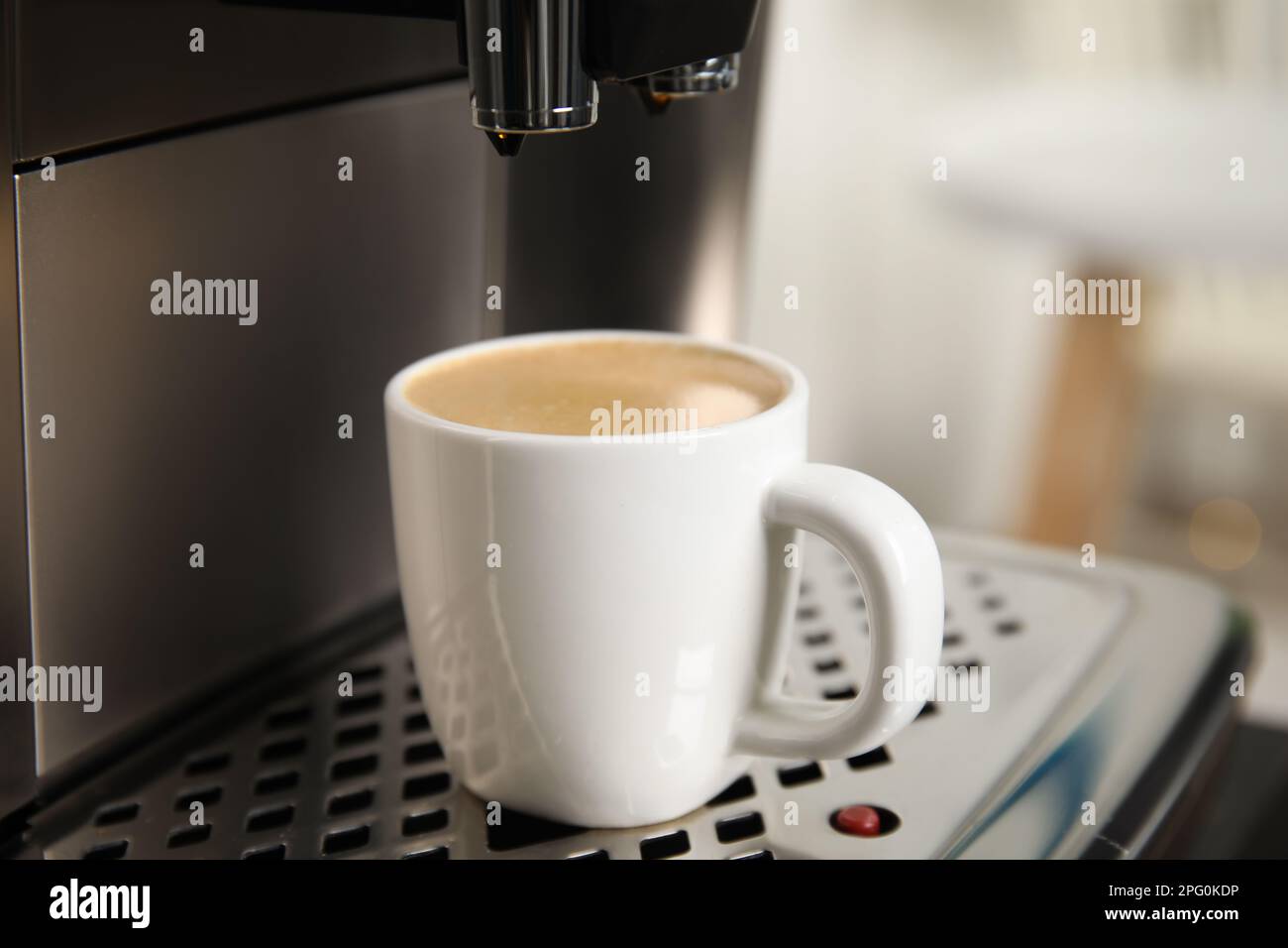 Macchina espresso con tazza di caffè fresco sul vassoio antigoccia sullo sfondo sfocato e primo piano Foto Stock