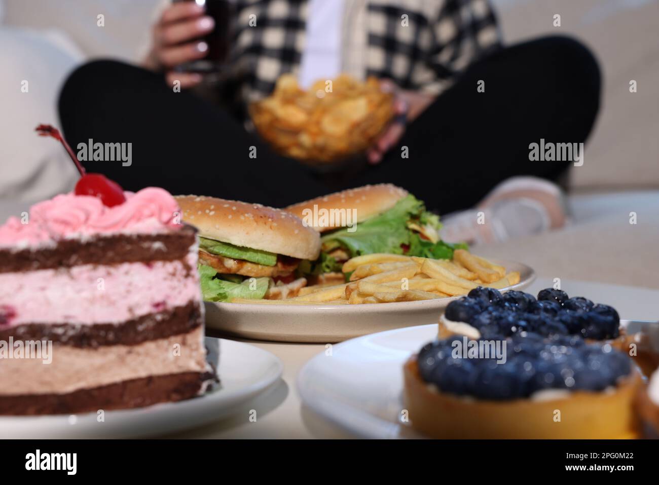 Donna in sovrappeso con patatine, concentrarsi su cibo non sano Foto Stock