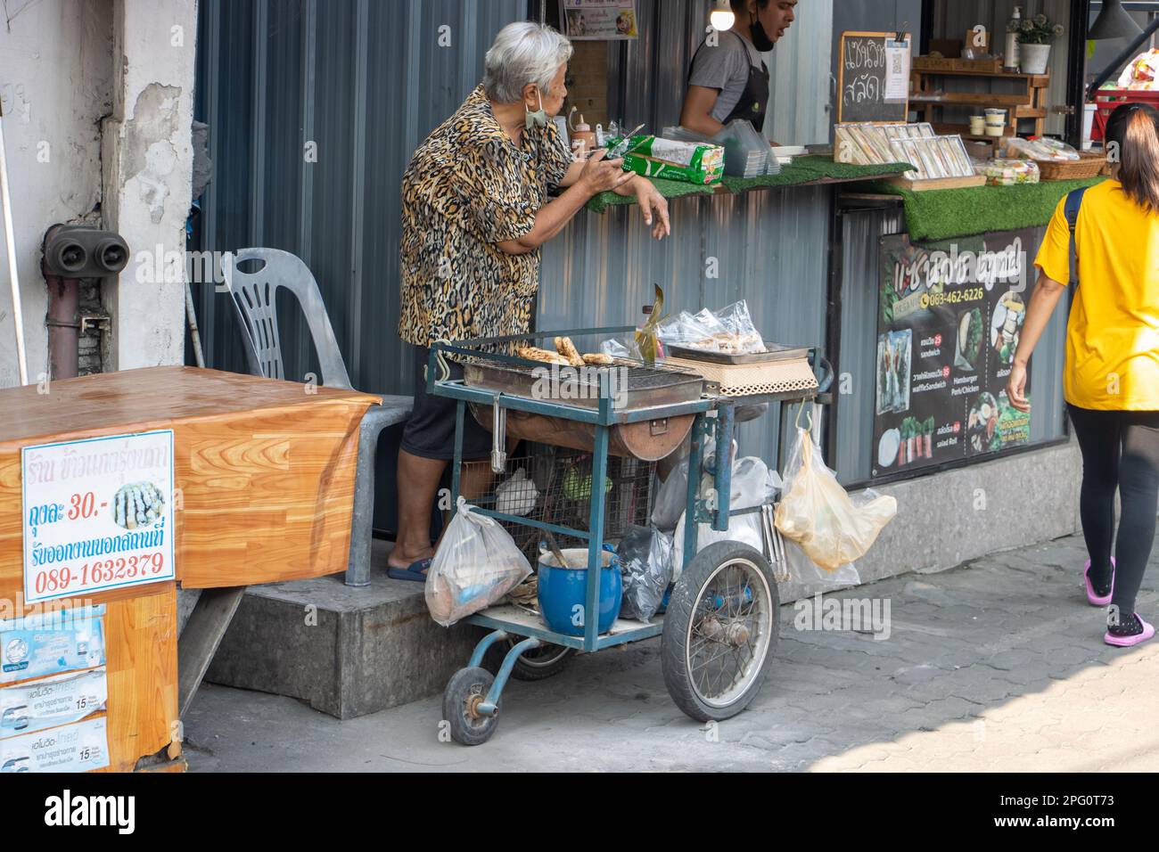 SAMUT PRAKAN, THAILANDIA, MAR 06 2023, la vecchia donna vende banane alla griglia sulla strada Foto Stock
