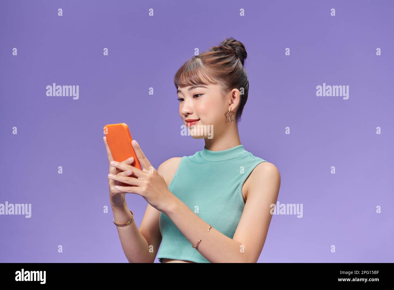 Bella ragazza millenaria isolata su sfondo viola messaggi di testo sul telefono cellulare Foto Stock