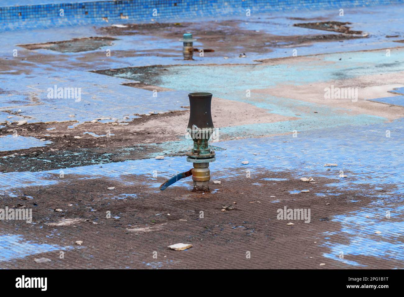 Ugello di fontana urbana con limo in una vasca sporca per la manutenzione e la pulizia Foto Stock