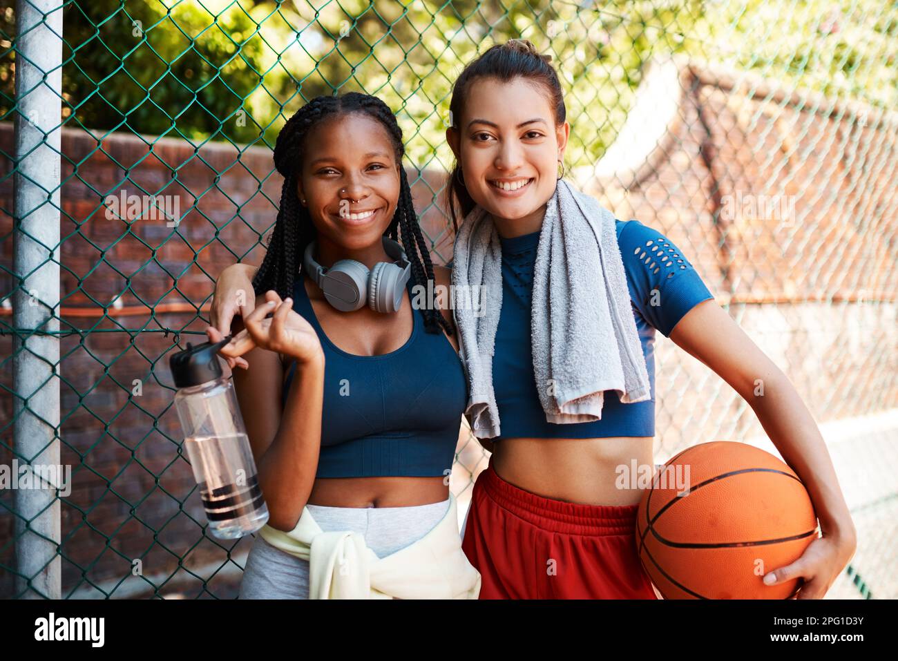 Erano i migliori amici e amanti del basket. Ritratto di due giovani donne sportive in piedi contro una recinzione su un campo sportivo. Foto Stock