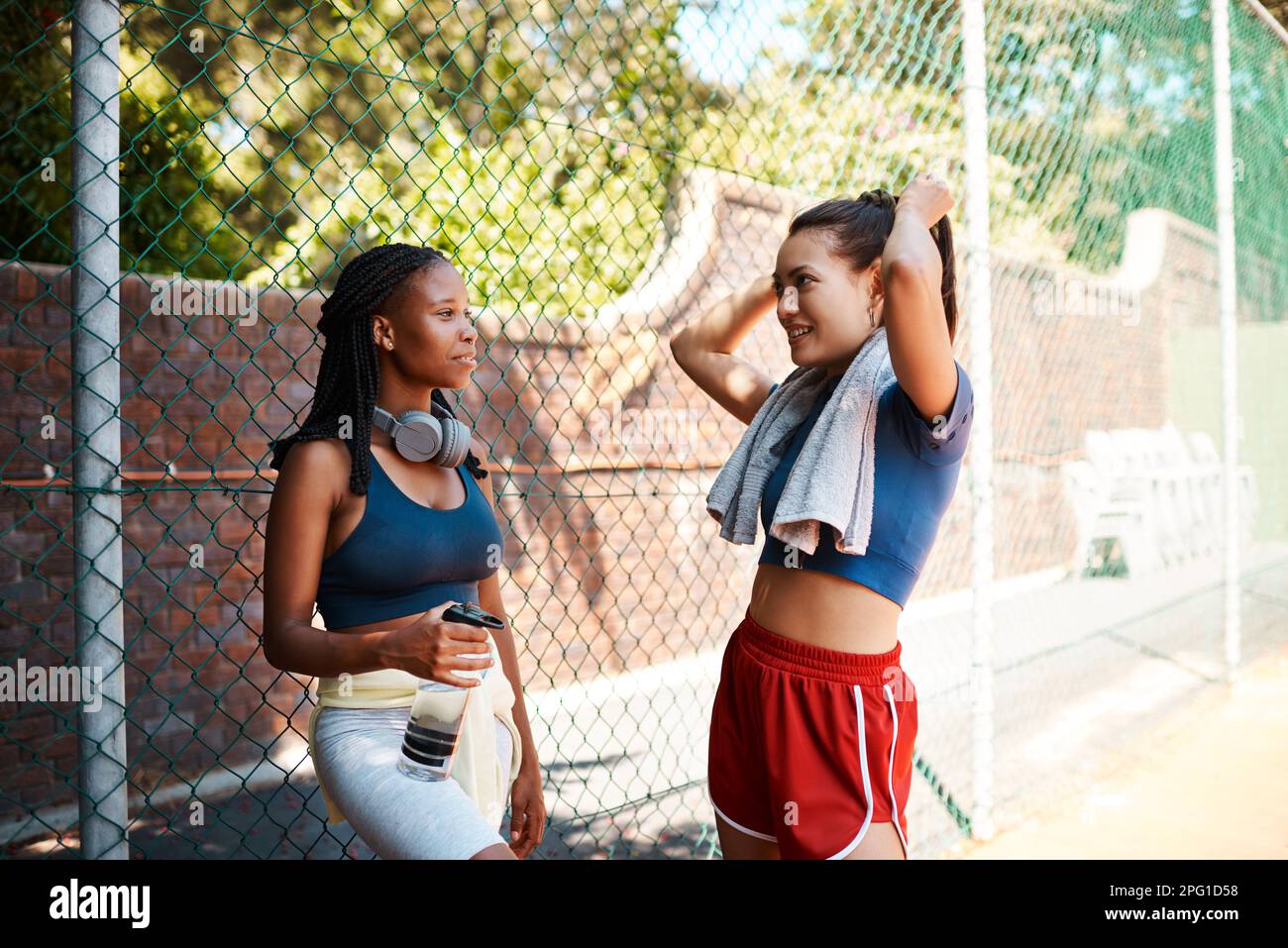 IM pronto per la prossima sessione. due giovani donne sportive che chiacchierano tra loro contro una recinzione all'aperto. Foto Stock