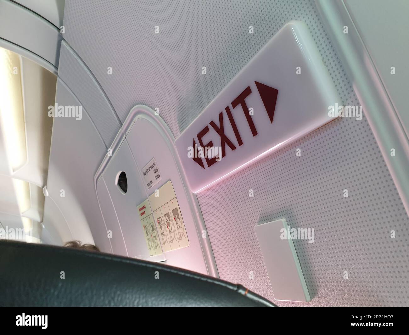 luce di uscita e porte nella fila delle uscite di emergenza posti a sedere su un aeromobile airbus a bordo a metà volo Foto Stock