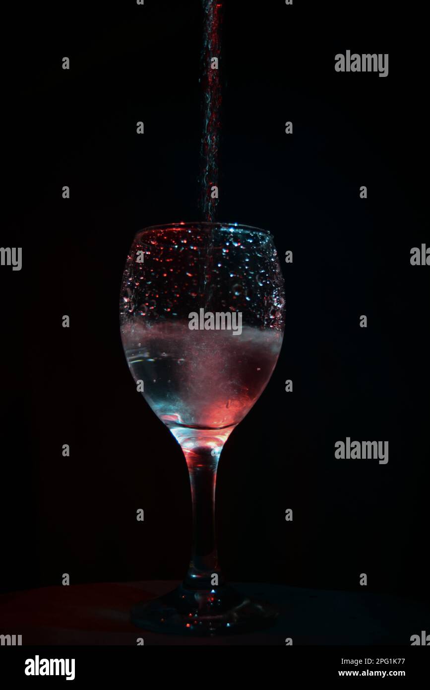 Bicchiere di vino ripieno di liquido su sfondo nero, fotografia a lunga esposizione Foto Stock