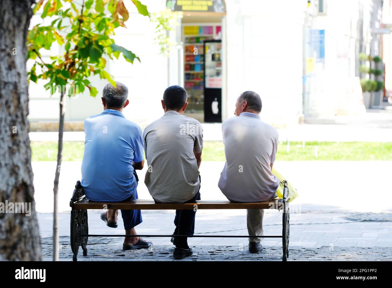 Samarkand Uzbekistan tre uomini siedono su una panchina all'ombra nel vecchio quartiere russo della città di Samarkand nell'agosto 2022 Foto Stock