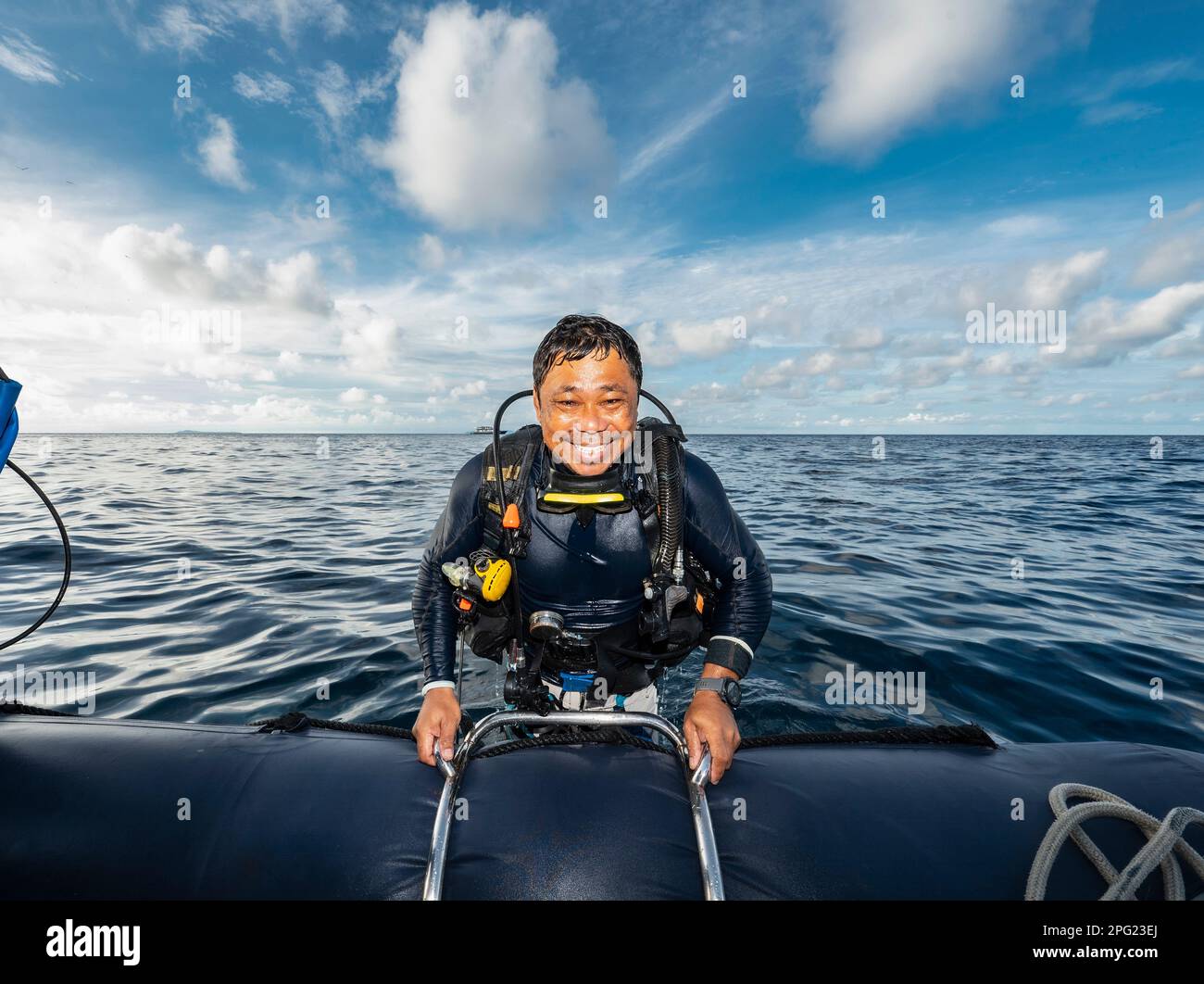 Tuffatore che sale in gommone dopo un'immersione nel mare di banda Foto Stock