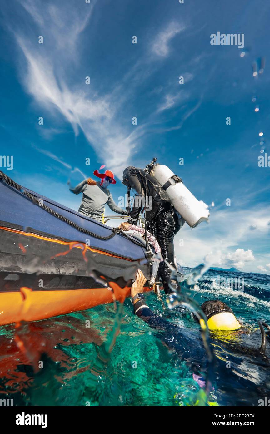 Tuffatore che sale in gommone dopo un'immersione nel mare di banda Foto Stock