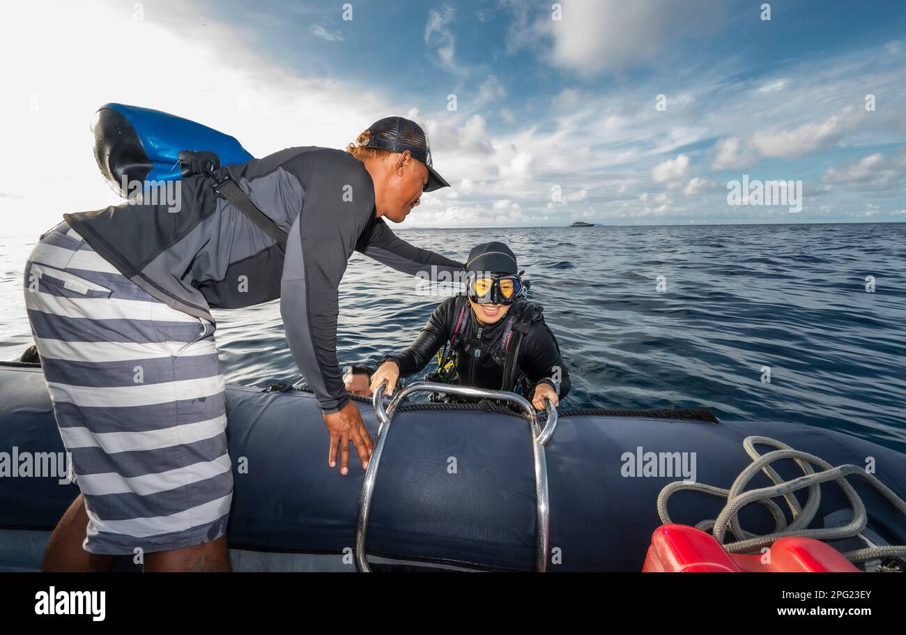 Tuffatore che sale in gommone dopo un'immersione nel mare di banda Foto Stock