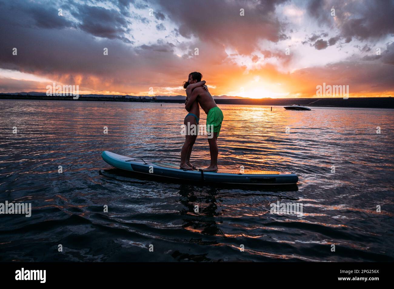 Due adolescenti che si abbraccia a bordo di pagaia al tramonto Foto Stock