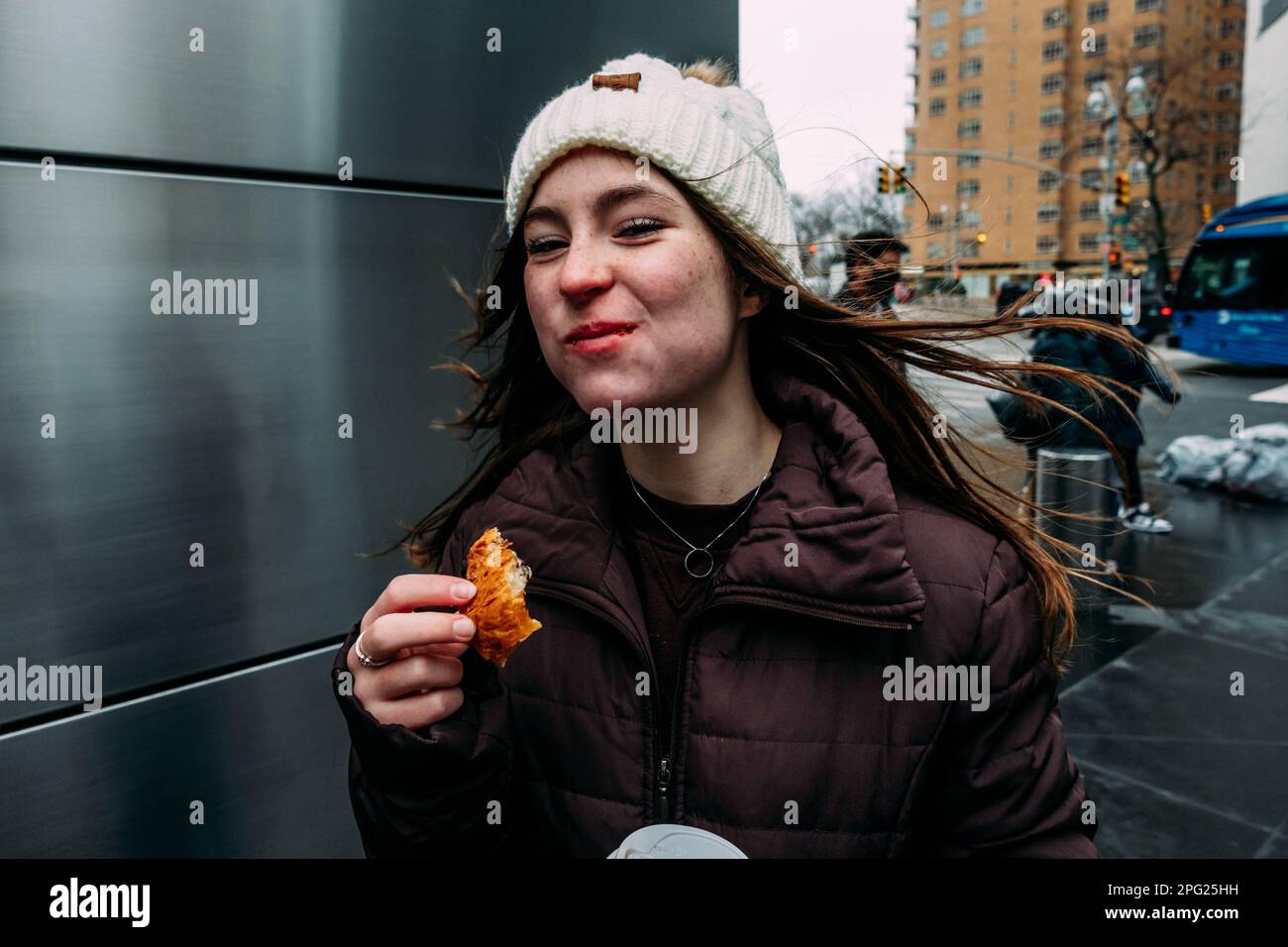 Ragazza teen che mangia il pane sull'angolo della strada Foto Stock