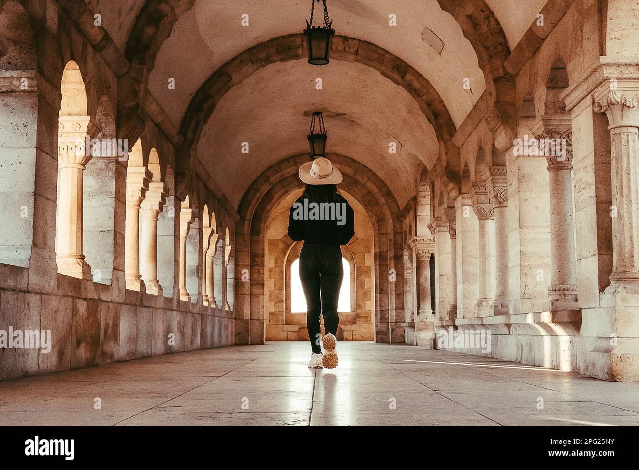 foto di scorta di una ragazza con cappello in corridoio con finestre architettoniche Foto Stock