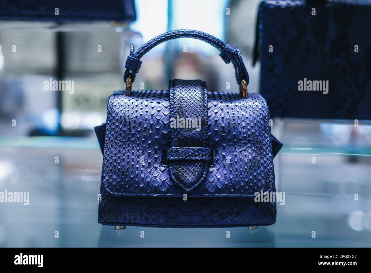 Borsa da donna in pitone in pelle blu su un piedistallo in un negozio Foto Stock