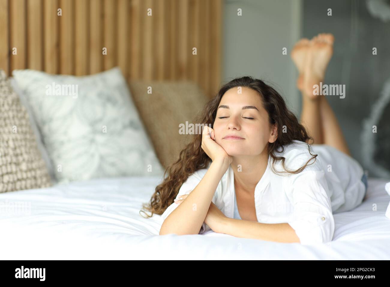 Felice bella donna sdraiata sul letto rilassante Foto Stock