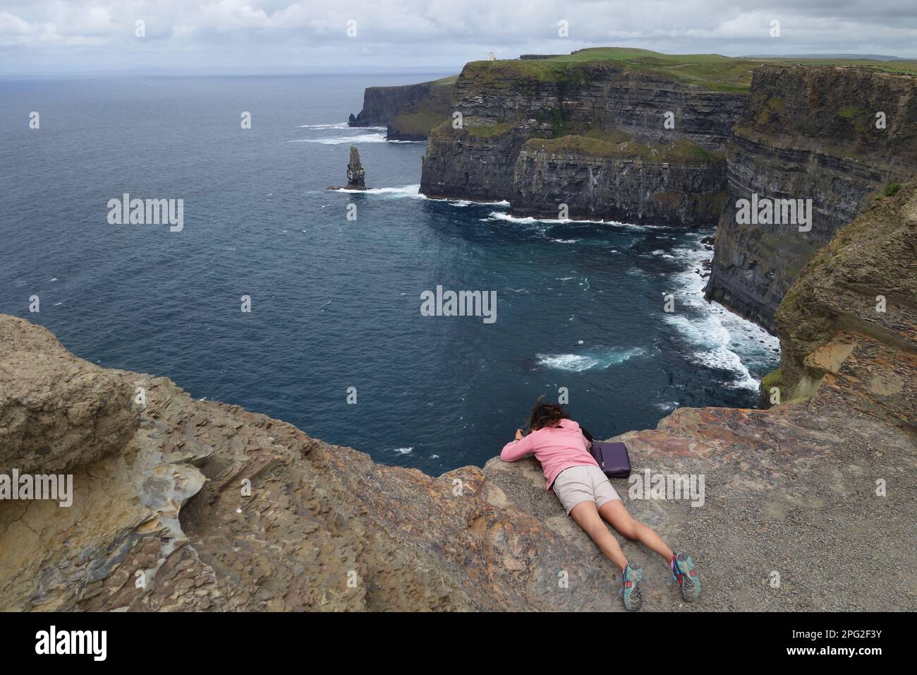 Giovane donna che guarda le scogliere di Moher, Irlanda Foto Stock