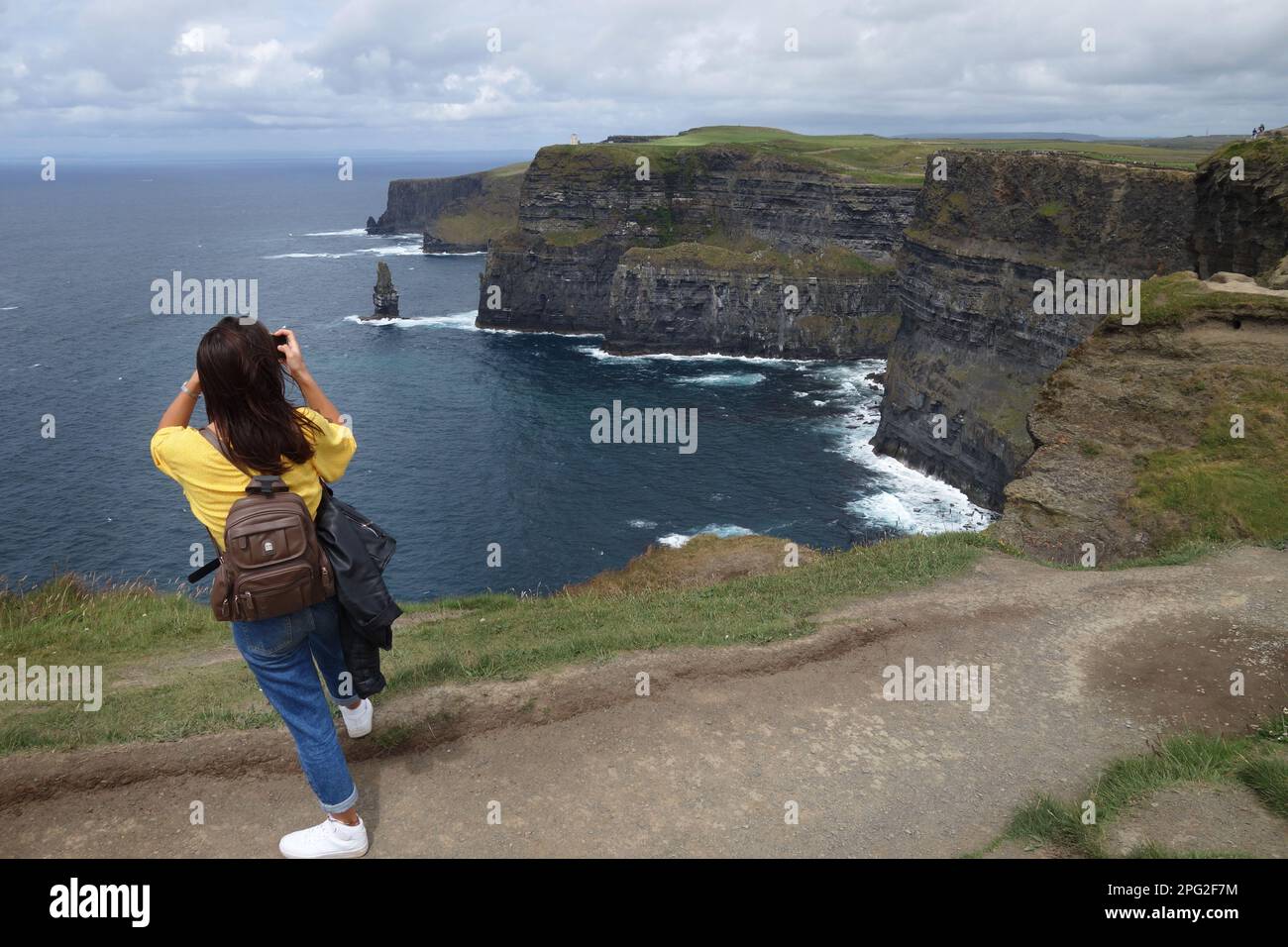 Giovane donna che fotografa le scogliere di Moher, Irlanda Foto Stock