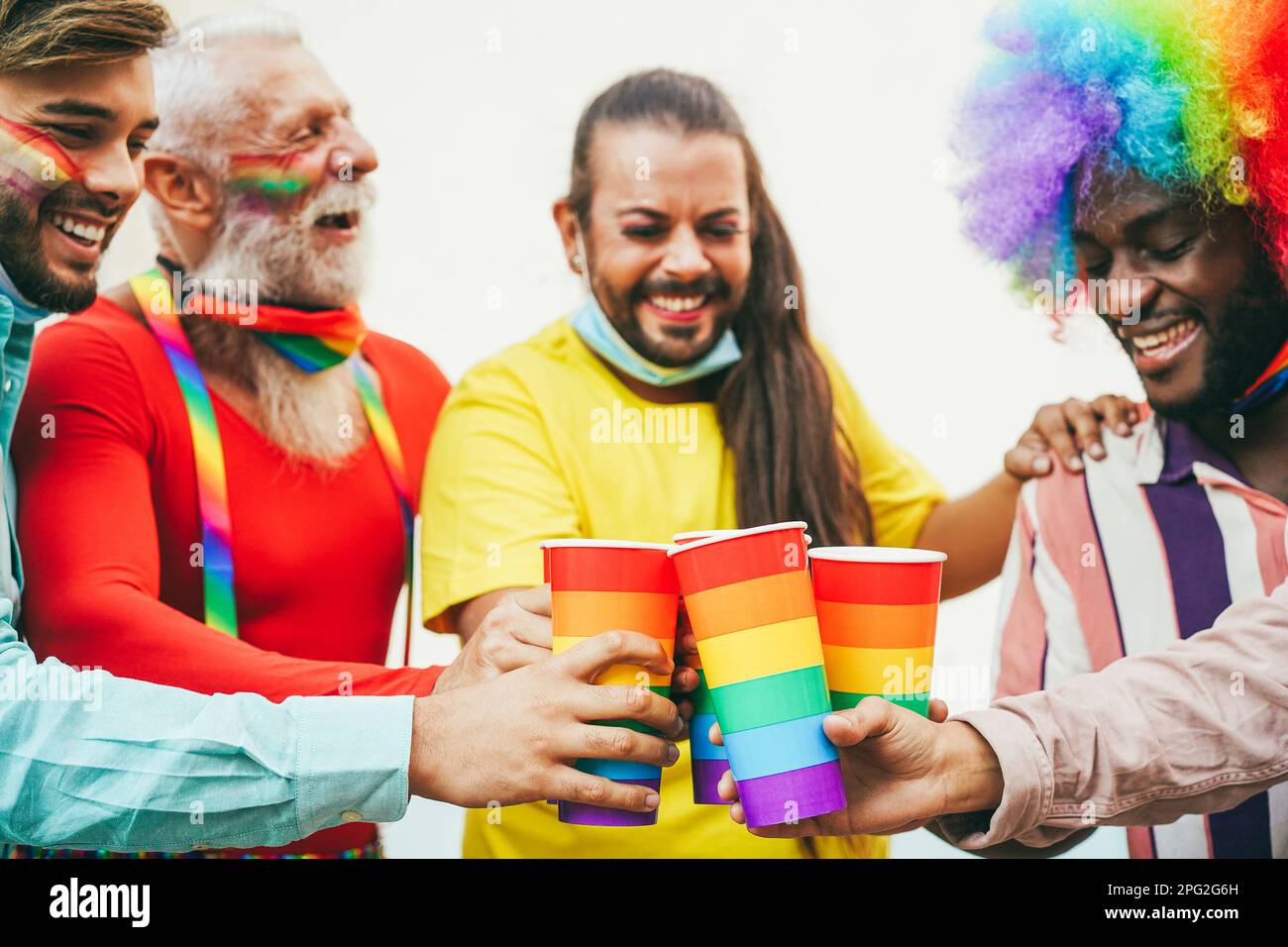 Persone gay multirazziali che indossano maschere di sicurezza mentre allietano con gli occhiali arcobaleno alla parata di orgoglio all'aperto - fuoco sugli occhiali Foto Stock