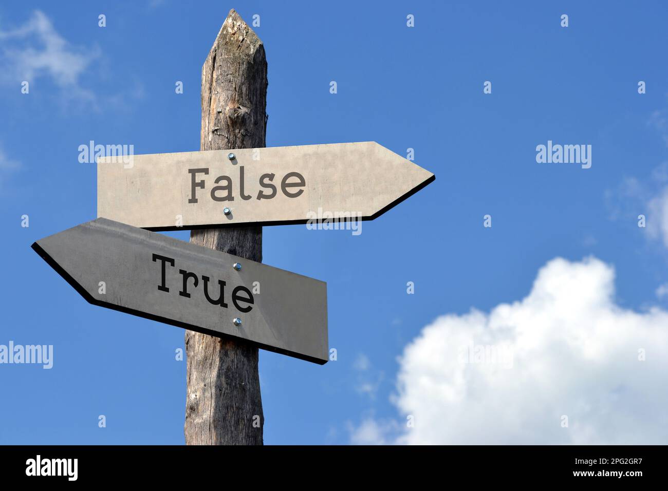 Vero e falso - cartello in legno con due frecce, cielo con nuvole Foto Stock
