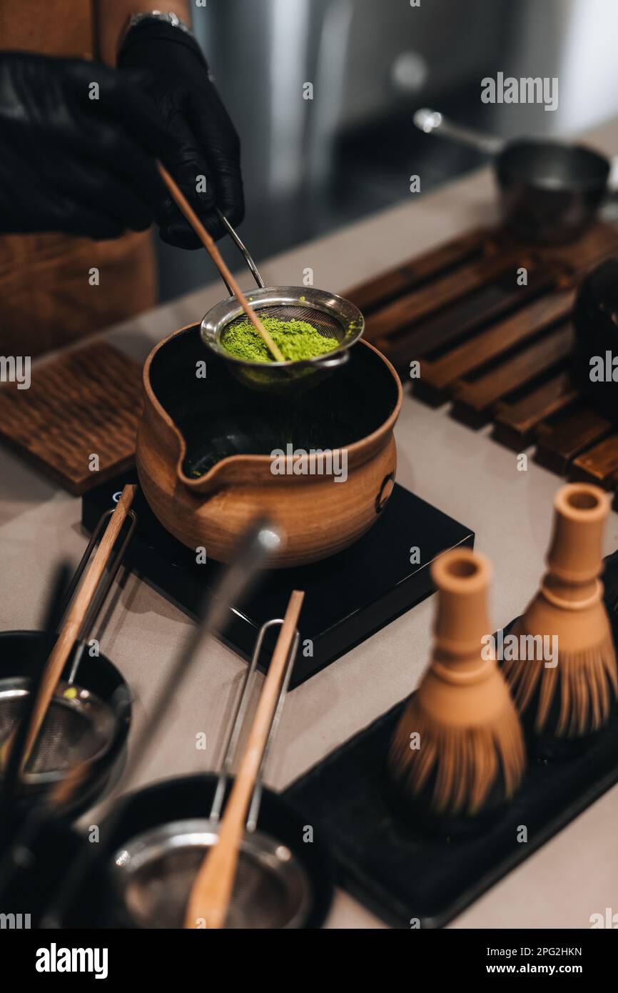 Processo di preparazione del tè verde Matcha giapponese. Utensili tradizionali realizzati con materiali organici naturali. Scatto verticale Foto Stock