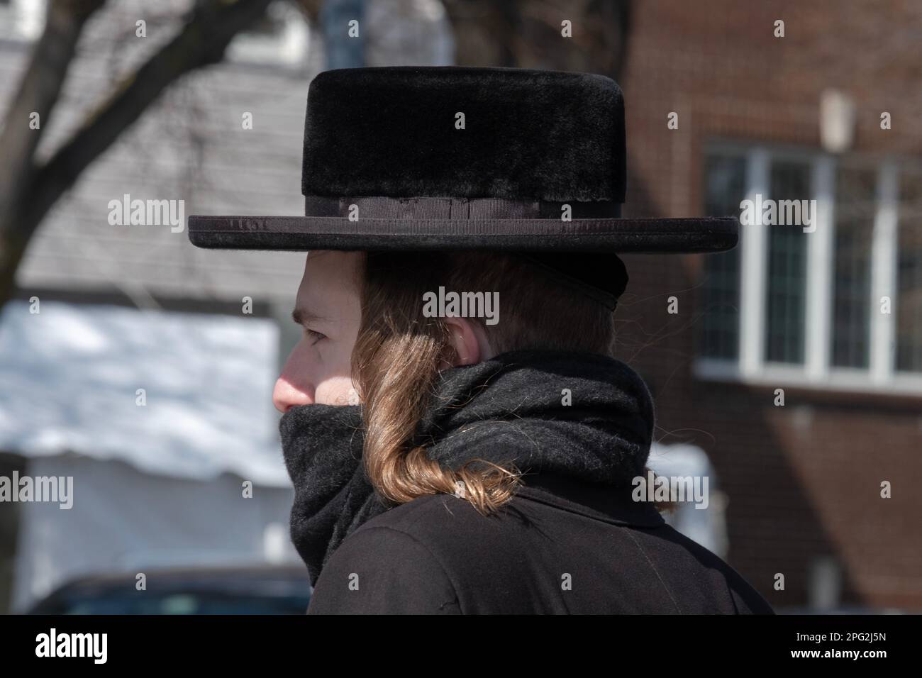 Un ebraico hassidico ortodosso con un lungo peyot riccio, un cappello nero e una sciarpa che gli copriva la bocca. A Brooklyn, New York, in una fredda giornata invernale Foto Stock