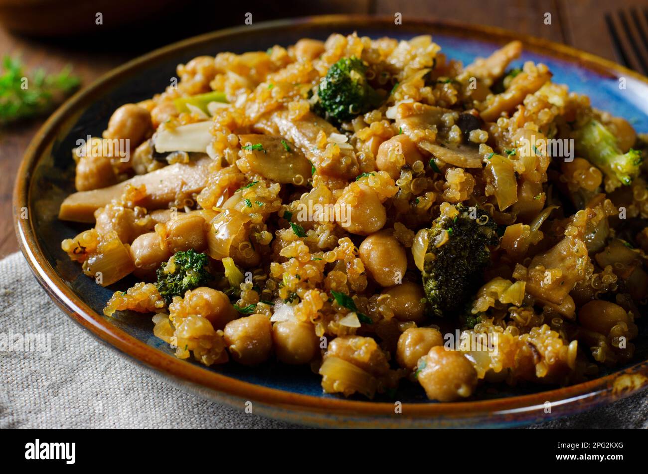 Quinoa con ceci, funghi e broccoli, pasto sano, cibo vegetariano, Sfondo rustico scuro Foto Stock