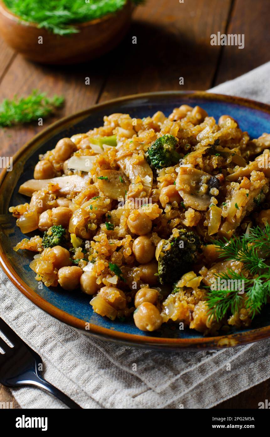 Quinoa con ceci, funghi e broccoli, pasto sano, cibo vegetariano, Sfondo rustico scuro Foto Stock